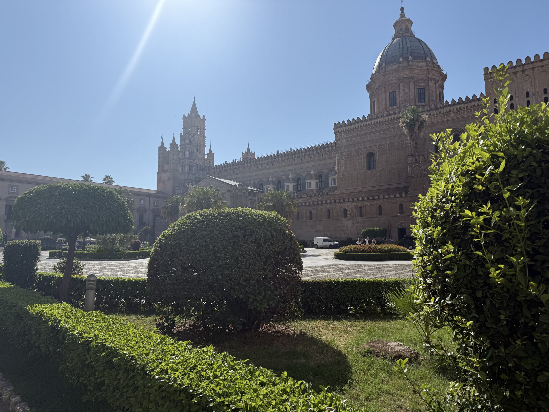 A historic Sicilian cathedral viewed across a formal garden