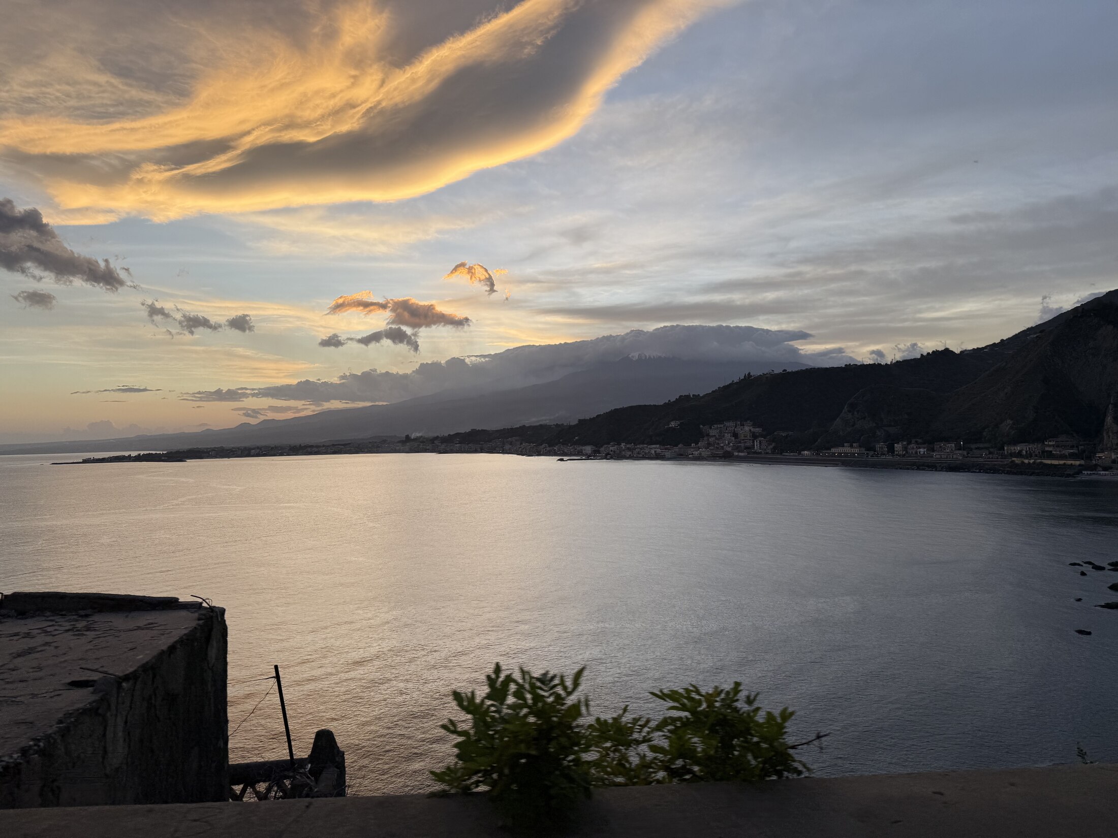 Golden clouds and evening light above a calm Sicilian bay